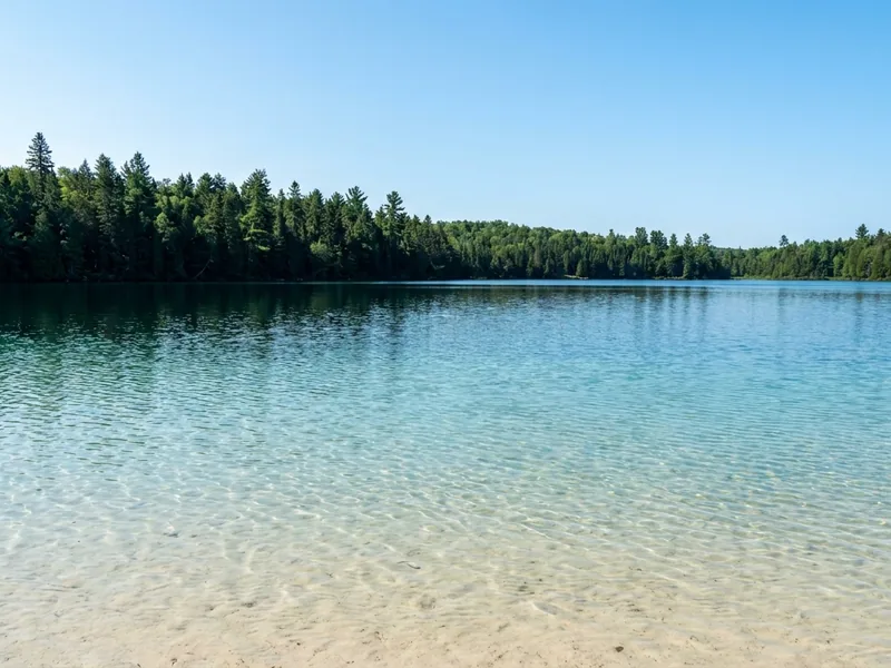 Sandy shoreline and clear water at Lake Clear, New York