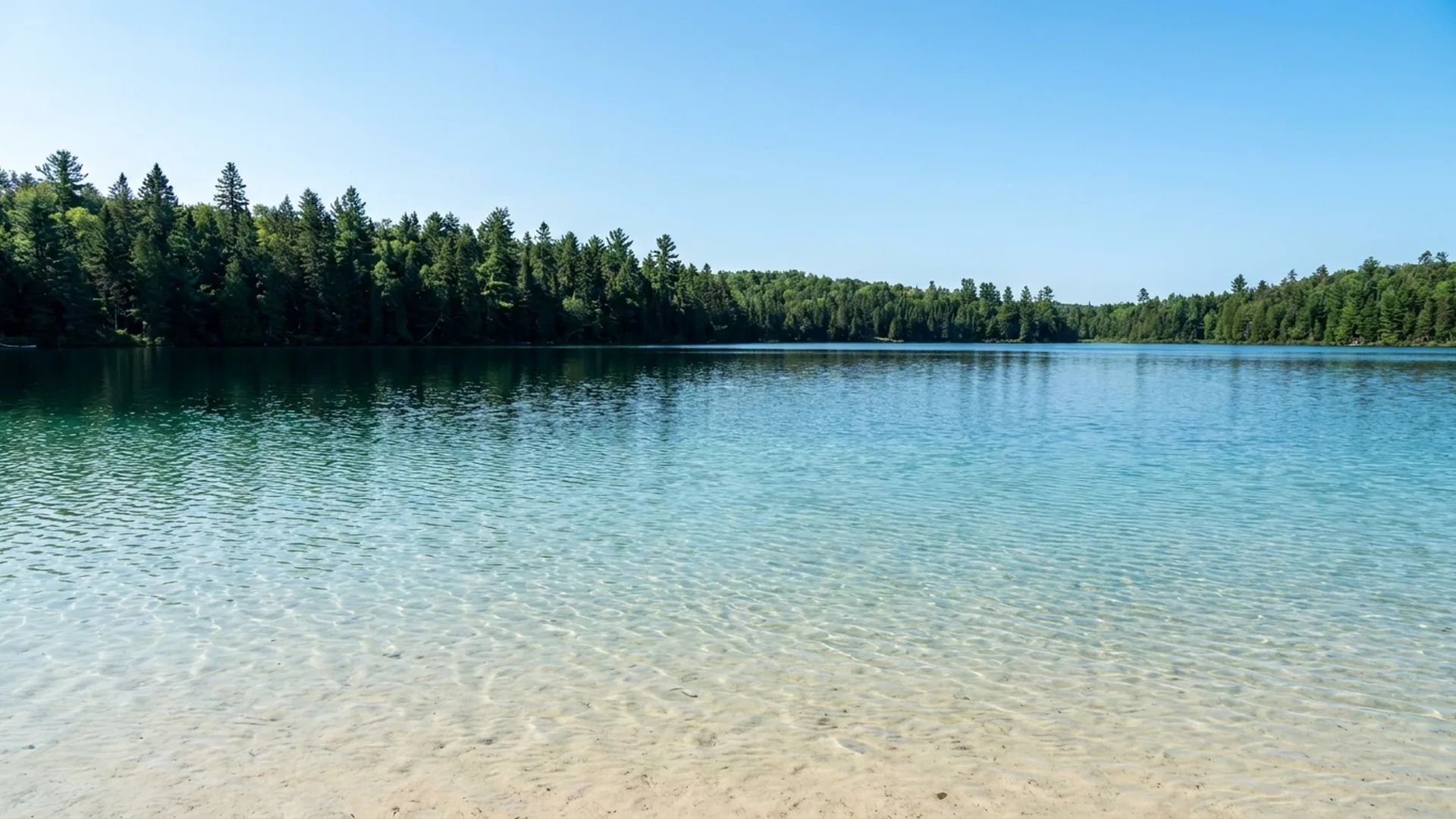 Clear shallow water over a naturally sandy shoreline at Lake Clear, New York