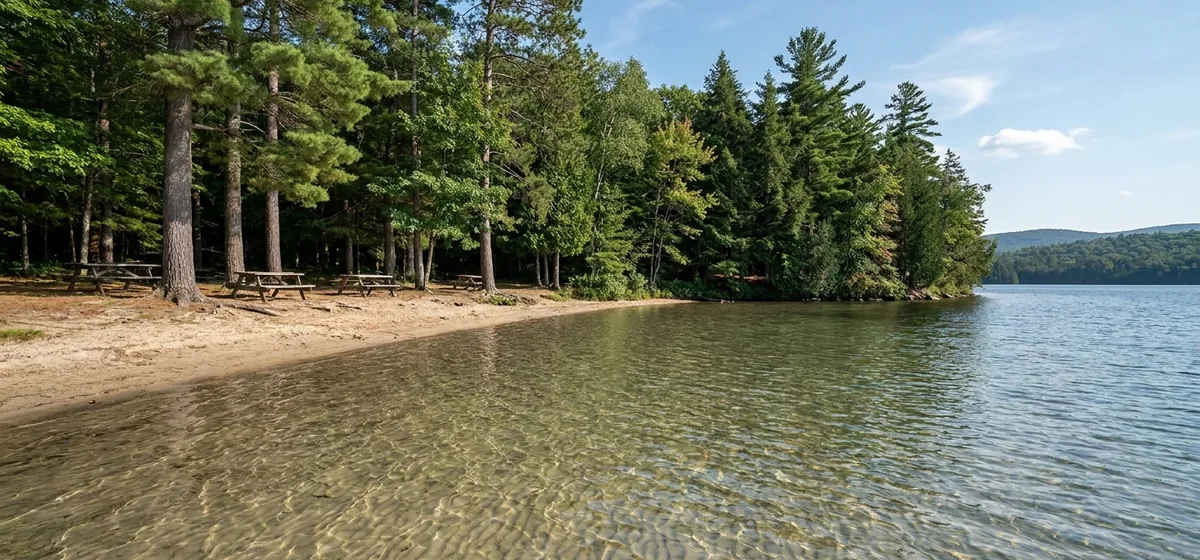 Sandy public beach and shallow clear water at Lake Clear, New York