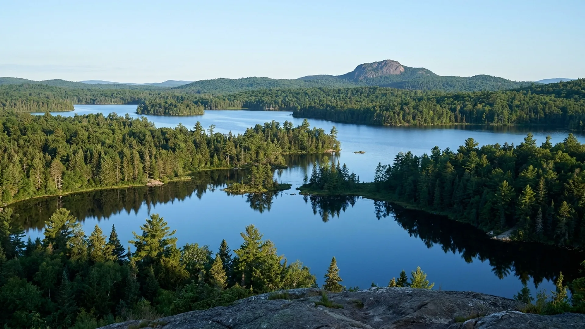 Lower St. Regis Lake with pine-lined shoreline and rustic Adirondack buildings at Paul Smiths, New York